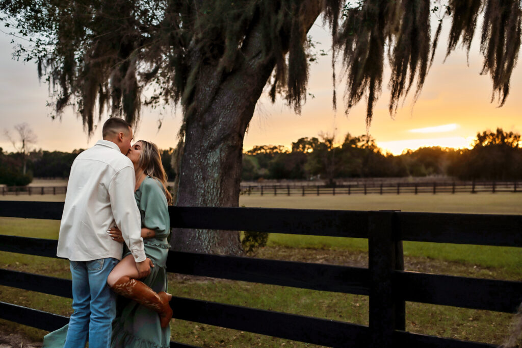 couple kissing under spanish moss tree at engagement session