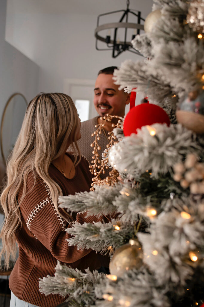 couple decorating christmas tree for engagement session 