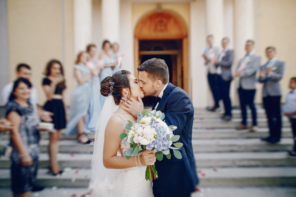 outdoor wedding venues in Florida. A young and beautiful bride is standing near house with her husband.